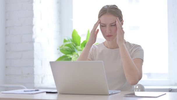 Jeune femme ayant mal à la tête tout en travaillant sur ordinateur portable
 - Photo, image