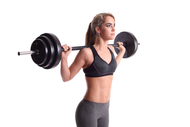 smiling sporty woman exercising with barbell on a white background - Photo, image