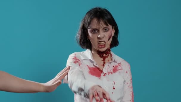 Frightening weird looking zombie angered by vaccine immunity injection. Creepy evil brain-eating monster with bloody and deep wounds and scars getting vaccinated because of pandemic on blue background - Footage, Video