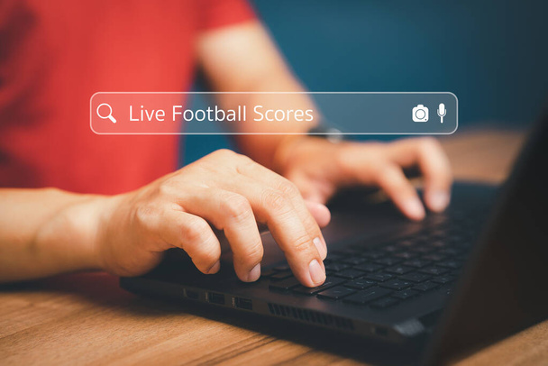Ręka fana futbolu pracuje z laptopem na biurku w domu. Wyszukiwanie Przeglądanie danych internetowych za pomocą paska wyszukiwania. Koncepcja sieci technologii wyszukiwarki. - Zdjęcie, obraz