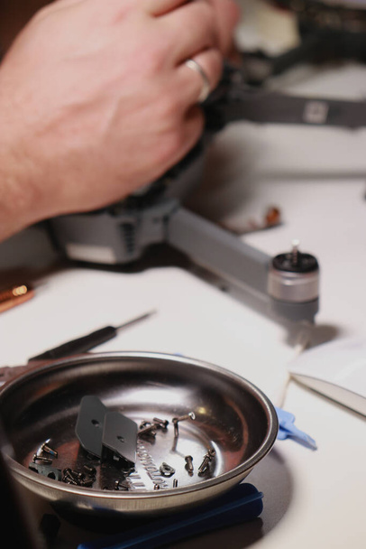 close up of mans hands repairing a drone on white table with different tools. High quality photo - Photo, Image