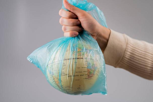 A woman is holding a globe in a plastic bag on a white background - Foto, Bild