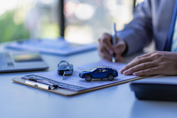Koncept prodeje automobilů, obchodní zástupci dát klíče k zákazníkům na stole s malými vzorky aut a pojištění kanceláře. - Fotografie, Obrázek