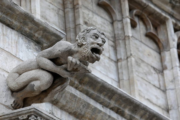 Чудовищная статуя с почти человеческими чертами, называемая горгулья на фасаде исторического здания - Фото, изображение