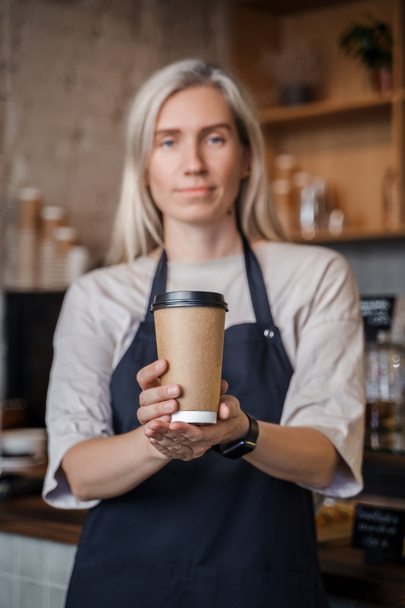 Snímek staré barmanky pracující v kavárně s blond vlasy a šálek kávy. - Fotografie, Obrázek