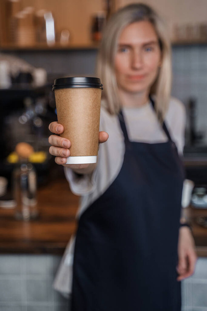 Фото женщины-бармена, работающей в кофейне со светлыми волосами и кофейной чашкой. - Фото, изображение