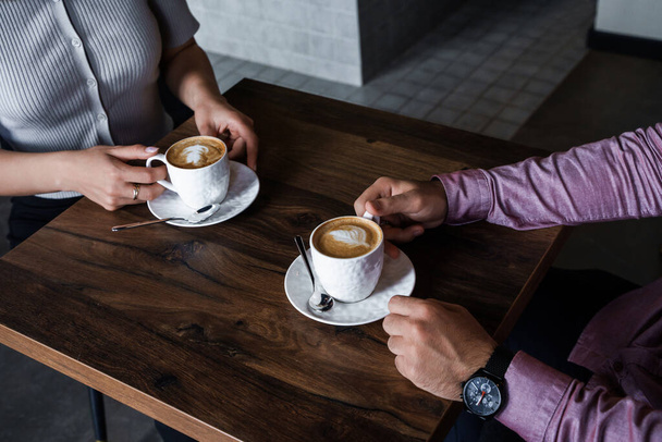 Młoda para przy kawie pije capuccino w nowoczesnej kawiarni. - Zdjęcie, obraz