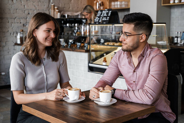 Shot ženy a muže mluví pití horké kávy v kavárně. - Fotografie, Obrázek