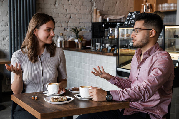 Laukaus nainen ja mies puhuu juo kuumaa kahvia kahvilassa. - Valokuva, kuva
