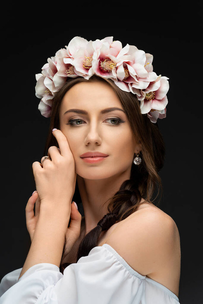 Beautiful young brunette woman wearing a delicately pink floral wreath. Wedding headdress for girls. Ukrainian beauty. High quality photo - 写真・画像