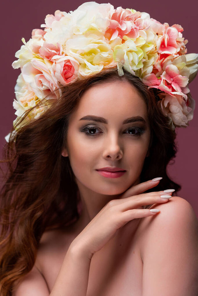 Portrait of a beautiful girl in a delicate wreath of flowers, with long red flowing hair. The concept of perfumery and cosmetics, or beauty salon. High quality photo - Photo, Image