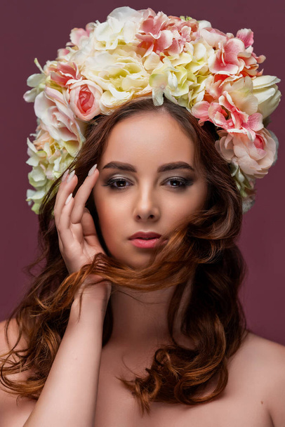 Portrait of a beautiful girl in a delicate wreath of flowers, with long red flowing hair. The concept of perfumery and cosmetics, or beauty salon. High quality photo - Fotoğraf, Görsel