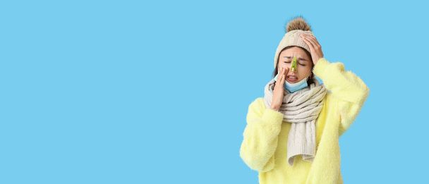 Ill young woman with clothespin on her nose against blue background with space for text - Photo, Image
