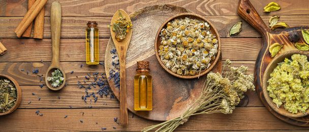 Composition with dry herbs and bottles of essential oil on wooden background, top view - Photo, Image