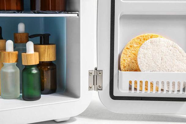 Petit réfrigérateur avec cosmétiques naturels et éponges sur fond blanc, gros plan - Photo, image