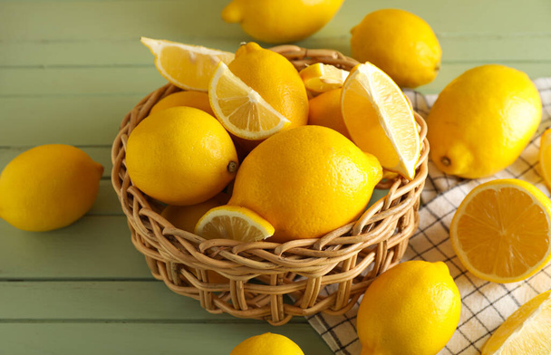 Basket with fresh lemons on color wooden background, closeup - Photo, image