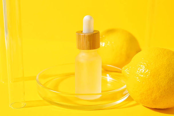 Bottle of vitamin C serum on yellow background - Foto, afbeelding