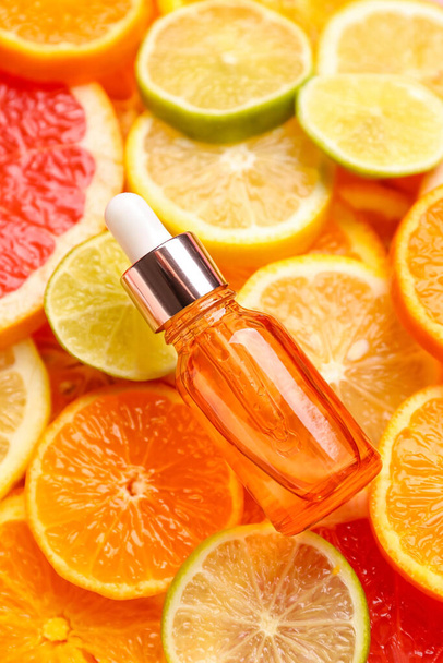 Fles met vitamine C serum op schijfjes citrusvruchten - Foto, afbeelding