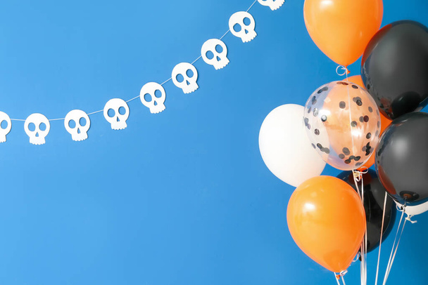 Balões de Halloween e crânios humanos de papel pendurados na parede azul - Foto, Imagem