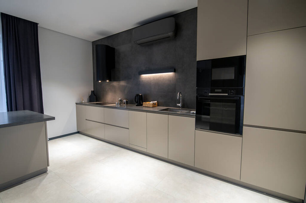 Interior of a stylish one-wall kitchen with the modern built-in double wall oven and cabinets - Fotografie, Obrázek