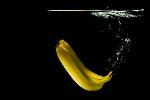Two ripe bananas floating underwater isolated on black background - Fotoğraf, Görsel