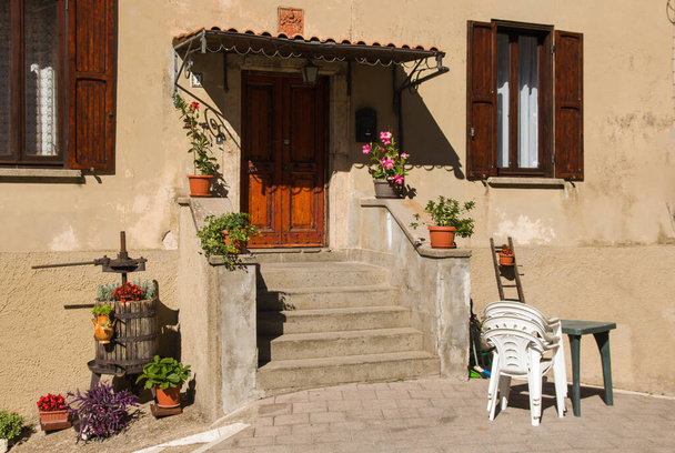 Romantic house entrance with garden furniture and flower pots - Фото, изображение