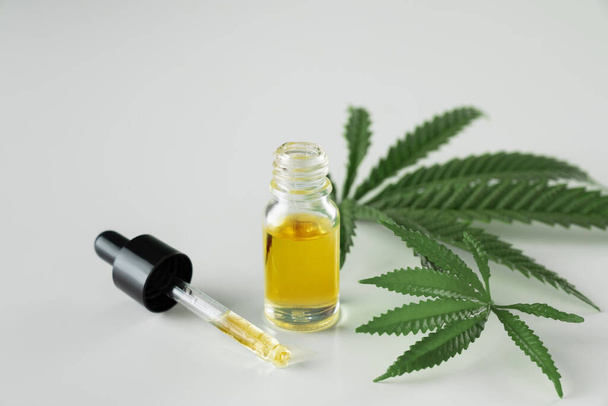 Cannabis sativa hennepblad met container CBD olie met druppeldeksel op witte achtergrond. Gewettigd marihuana concept. - Foto, afbeelding