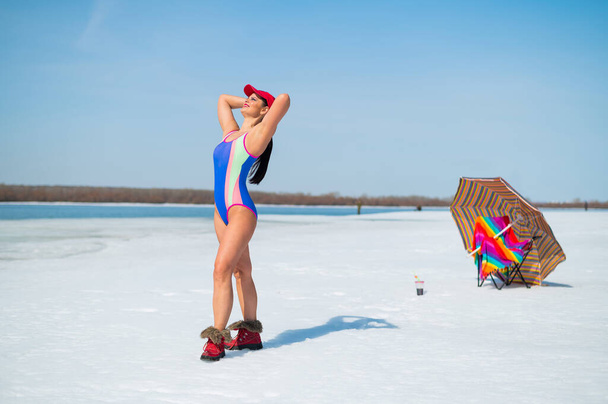 Caucasian woman in a swimsuit sunbathes on the snow in winter - Foto, afbeelding