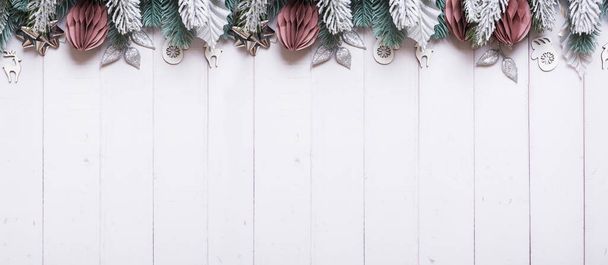 Christmas banner with flat lay snow pine trees, paper and wooden Christmas toys on wooden background. - Foto, Imagem