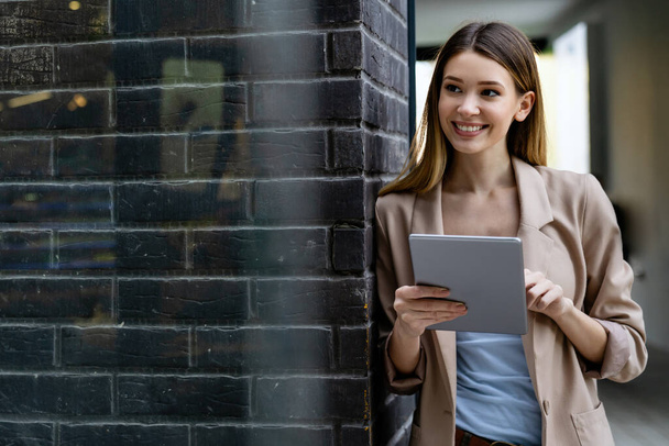 Portrait of young successful woman using digital tablet in urban background. Business people concept - 写真・画像