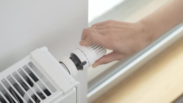 A mulher transforma o regulador da válvula termostática do radiador para aumentar ao máximo a temperatura do aquecedor na sala. Aquecimento do apartamento em tempo frio e geadas severas - Filmagem, Vídeo