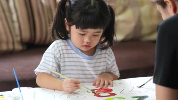 Carino piccolo bambino asiatico sorridente e sua madre pittura con vernici colorate utilizzando acquerello. Ragazza asiatica utilizzando pennello disegno a colori. Concetto di stile di vita. - Filmati, video
