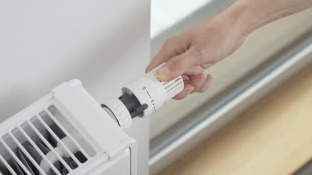 Žena otočí regulátorem termostatického ventilu radiátoru tak, aby se teplota ohřívače v místnosti zvýšila na maximum. Vytápění bytu za chladného počasí a prudkých mrazů - Záběry, video