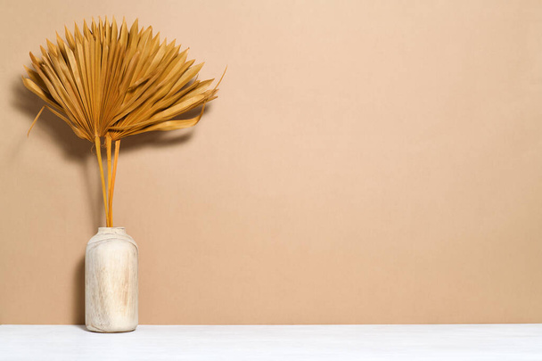 Vase mit palmtrockenen Blättern auf beigem Hintergrund - Foto, Bild