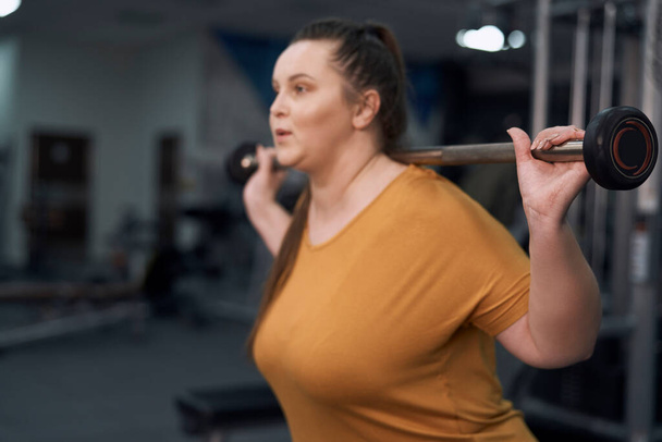 Blanke vrouw met overgewicht gewichtheffen in de sportschool  - Foto, afbeelding