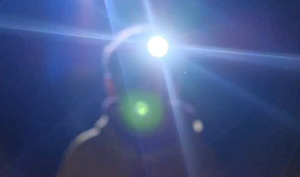 ragazzo con la torcia sulla testa al buio brilla in macchina fotografica di notte - Foto, immagini