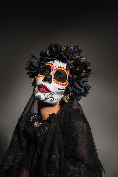 Portrait of woman in mexican day of dead costume looking at camera on black background  - Photo, Image