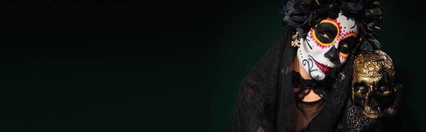 Woman with mexican day of dead makeup holding skull on dark green background, banner  - Photo, Image