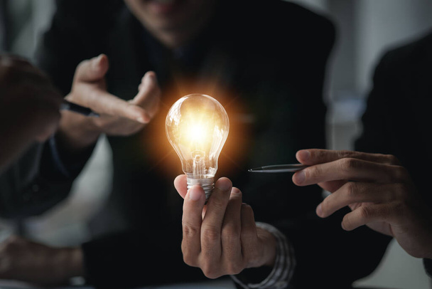 Empresario sostiene una lámpara brillante, nueva idea creativa. Innovación, lluvia de ideas, estrategias para hacer que el negocio crezca y sea rentable. Ejecución de conceptos, planificación estratégica y gestión de beneficios. - Foto, imagen