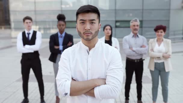 ryhmä monirotuisia liikemiehiä seisoo, keskittyä nuori aasialainen mies - Materiaali, video