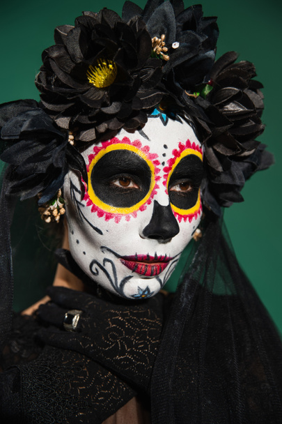 Mulher de coroa preta e dia de Halloween de maquiagem morte posando isolado no verde  - Foto, Imagem