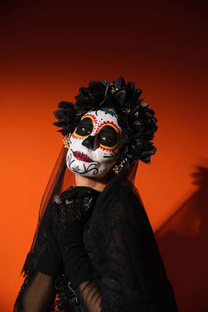 Santa Muerte cadılar bayramı kostümlü bir kadın kırmızı arka planda kameraya bakıyor.  - Fotoğraf, Görsel