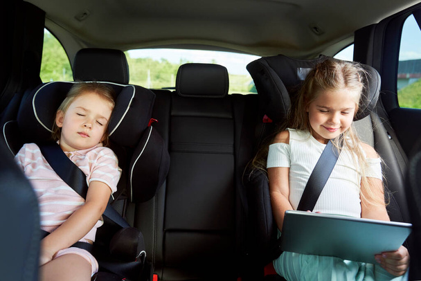 Две кавказские детки едут в машине на заднем сиденье - Фото, изображение