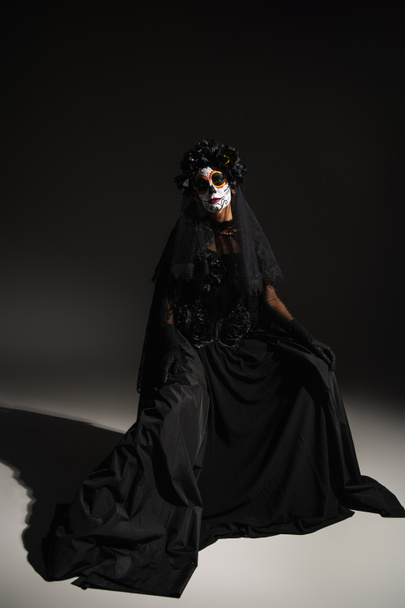 full length of woman in black dress and with spooky halloween makeup on dark background - Fotoğraf, Görsel