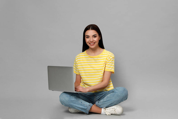Young woman with modern laptop on light grey background. Space for text - Zdjęcie, obraz