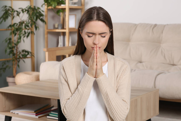 Woman with clasped hands praying at home - Photo, image