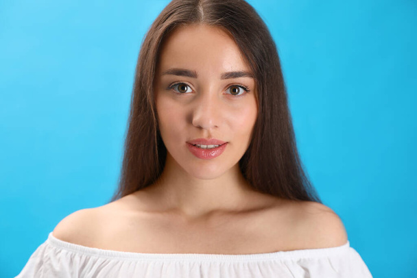 Portrait of beautiful young woman on light blue background, closeup - 写真・画像