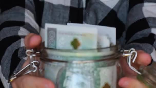 Polish zloty banknote saving money in glass jar. Unrecognizable woman moderate consumption and economy Collecting money. Tips. Business, finance, saving, banking and people concept. Extra money - Imágenes, Vídeo