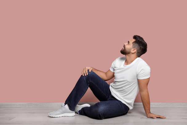 Young man sitting on floor near pink wall indoors. Space for text - Fotografie, Obrázek