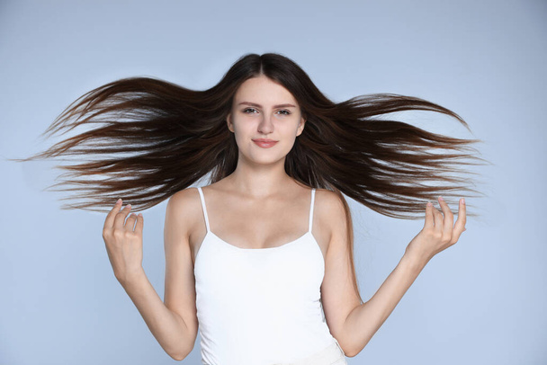 Young woman with strong healthy hair on light blue background - Foto, Imagen